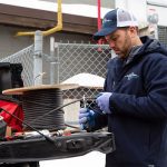 Contractor cutting self-regulating heat trace cable from reel on tailgate